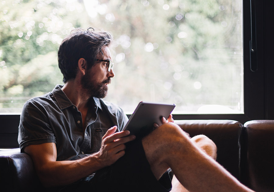 man-with-tablet-looking-out-window